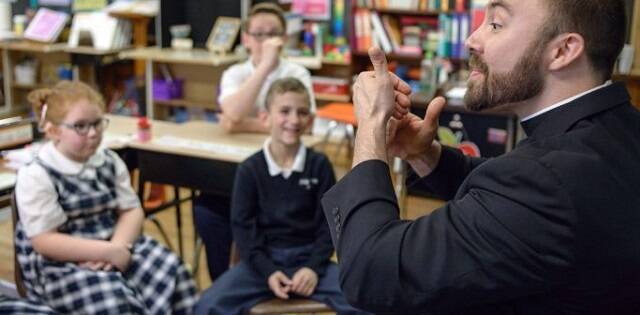 El padre Loomis, encargado de la pastoral de sordos en Filadelfia, explica a unos niños la lengua de signos