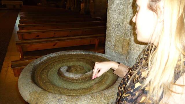 Mujer moja los dedos en una pila de agua bendita.
