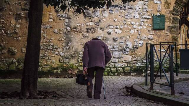 Un hombre anciano con muleta andando.