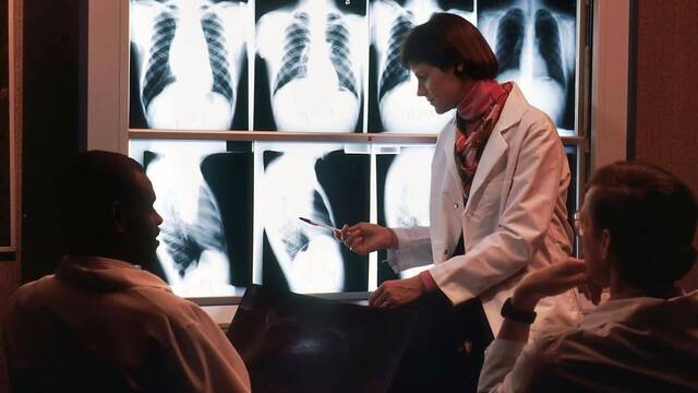 Tres médicos examinan unas radiografías.