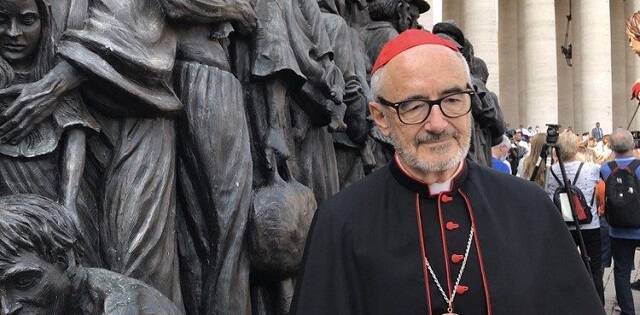 El cardenal Czerny junto a una estatua que representa el drama de los migrantes