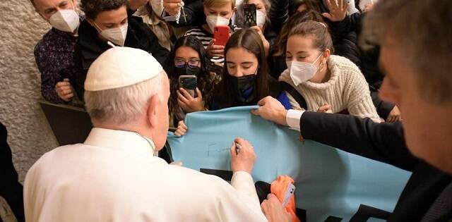 Francisco firma una pancarta que traen peregrinos al Aula Pablo VI, donde impartió su catequesis de los miércoles