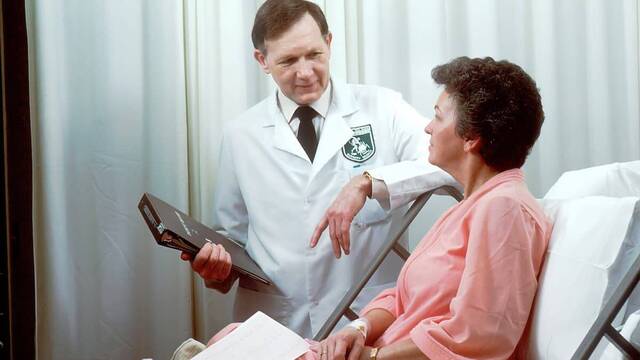 Un médico escucha a su paciente en la cama.