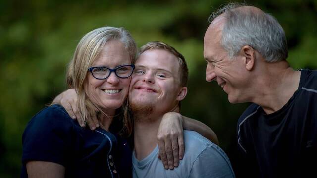 Padres abrazados a su hijo con síndrome de Down.