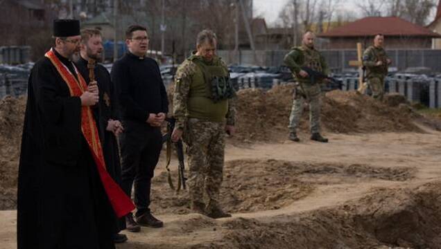 El arzobispo Shevchuk, con dos asistentes y militares ucranianos, ante la fosa común de Bucha el 7 de abril