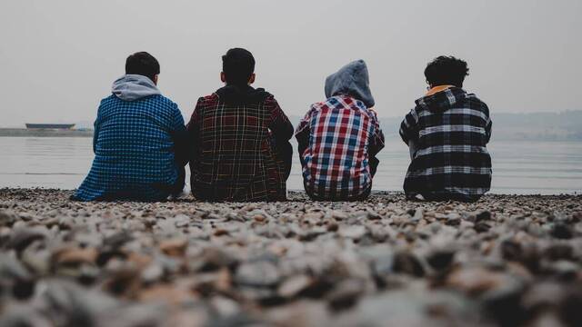 Cuatro adolescentes sentados en la playa.