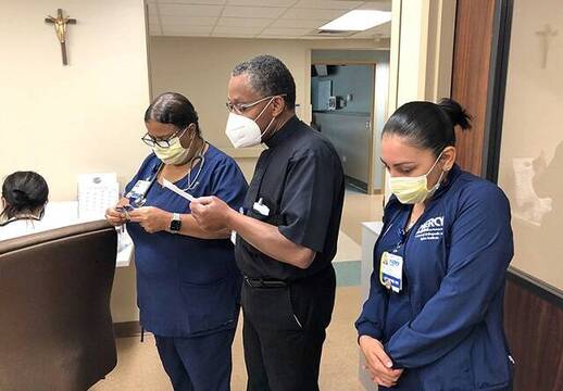 Un capellán reza con unas sanitarias en un hospital de Miami 