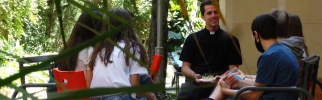 Sacerdote joven en el barrio de Gracia sentado con catequistas jóvenes