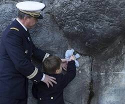 Un militar y un niño con peluche en la gruta de Lourdes