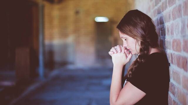 Chica joven rezando.