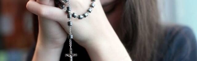 Una mujer rezando el rosario.  