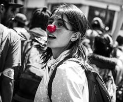 Chica joven en una manifestación con nariz roja de payaso.