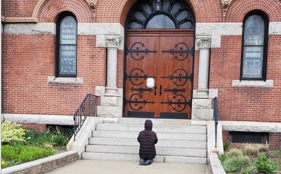 Una mujer reza ante la parroquia de Santa Teresa de Calcuta, en Dorchester, Boston, EEUU, cerrada por la pandemia, en 2020