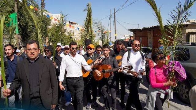 Curas con guitarras y peregrinos con palmas en Domingo de Ramos en Jerusalén 2023.