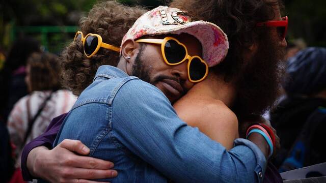 Tres personas abrazadas con gafas de sol de corazones.