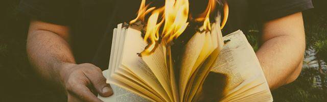 Un hombre sostiene un libro ardiendo.