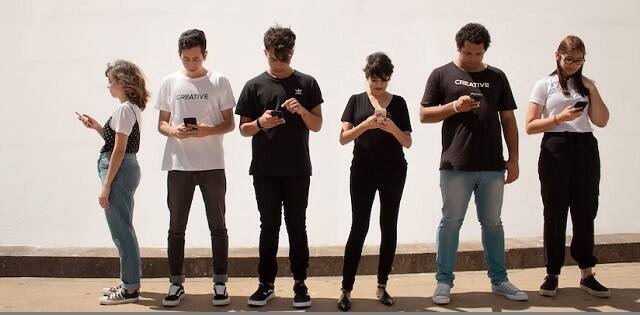 Jóvenes y adolescentes miran su móvil o iPhone