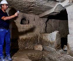 Un hombre ilumina una cueva arqueológica.