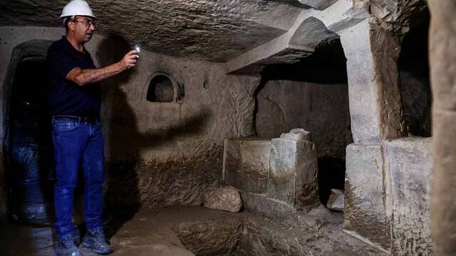 Un hombre ilumina una cueva arqueológica.