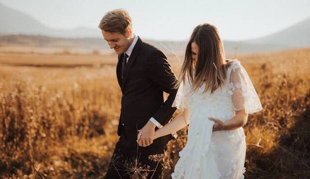 Recién casados pasean por el campo tomados de la mano - foto de Sandro Crepulja en Pexels