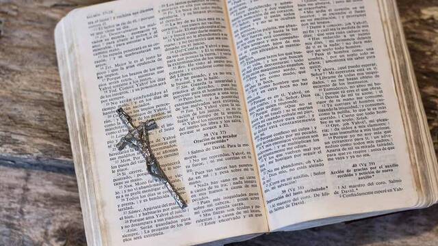 Biblia abierta con un crucifijo sobre ella.