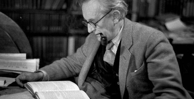 JRR Tolkien con pipa leyendo un libro en una foto en blanco y negro
