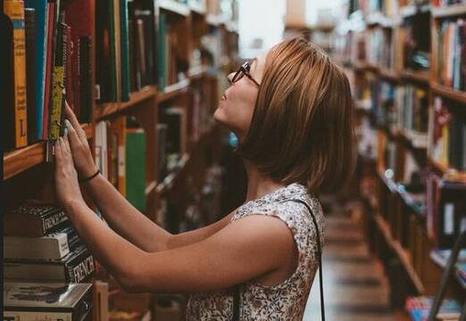 Una mujer busca libros entre estanterías - foto de Clay Banks en Unsplash