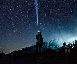 Hombre con linterna y cielo estrellado, foto de Hanson Lu