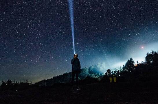 Hombre con linterna y cielo estrellado, foto de Hanson Lu