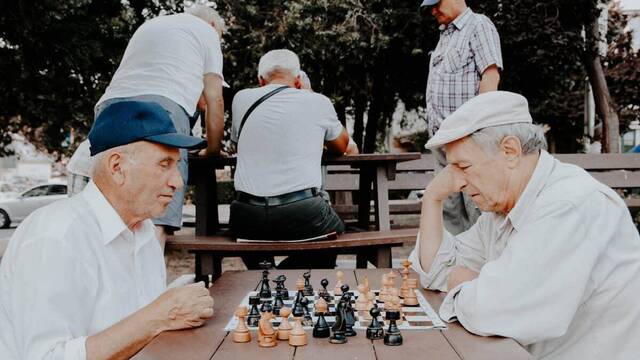 Dos ancianos juegan al ajedrez en un parque.