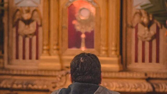 Hombre rezando ante el Santísimo.