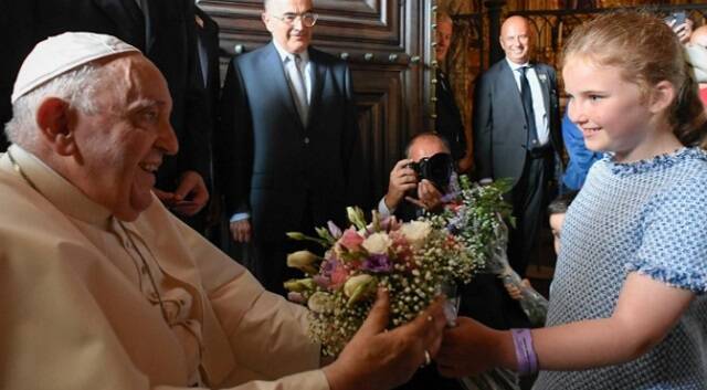Una niña entrega flores al Papa en los Jerónimos de Lisboa antes de las vísperas