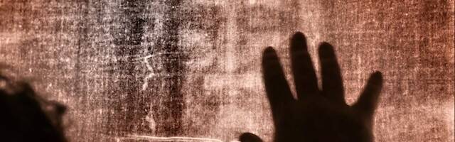 Una escena de 'The Shroud' en la que una mano se acerca a una imagen de la Sábana Santa.