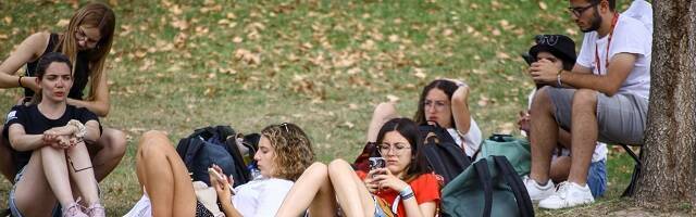 Jóvenes católicos esperan sentados en la hierba en la JMJ de Lisboa 