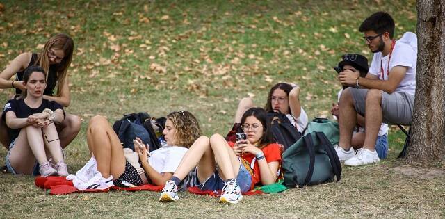 Jóvenes católicos esperan sentados en la hierba en la JMJ de Lisboa 