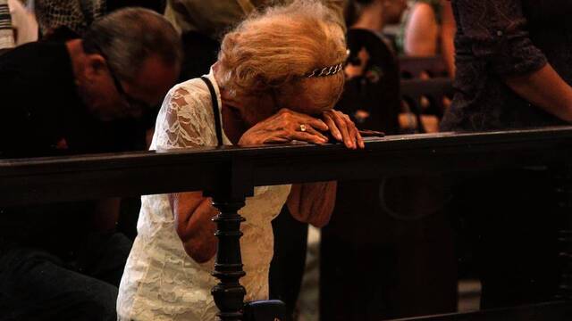 Mujer arrodillada rezando.