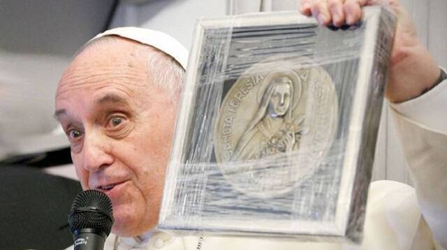 El Papa Francisco, en un viaje, muestra un grabado con la imagen de Santa Teresita de Lisieux