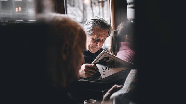 Una persona leyendo el periódico en una cafetería.