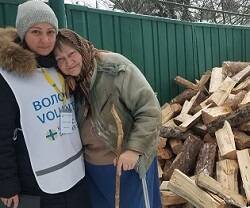 Una voluntaria de Cáritas repasa la entrega de madera para pasar el invierno a una anciana en Ucrania