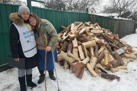 Una voluntaria de Cáritas repasa la entrega de madera para pasar el invierno a una anciana en Ucrania