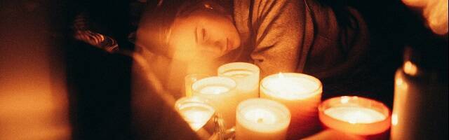 Una mujer joven con velas, quizá orando, en una foto de Harvey Robinson para Unsplash