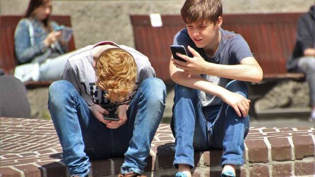 Dos chicos adolescentes mirando el móvil.