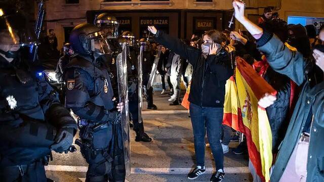 Unos jóvenes exhiben sus rosarios ante la Policía durante las manifestaciones ante la sede del PSOE en Madrid, en la calle Ferraz.