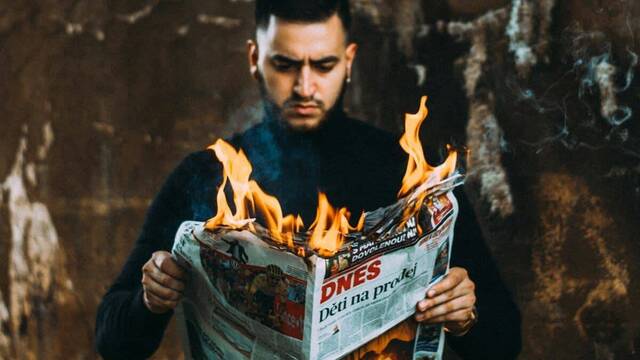 Un hombre lee un periódico que arde.