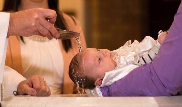 Bautizan un bebé en una pila bautismal