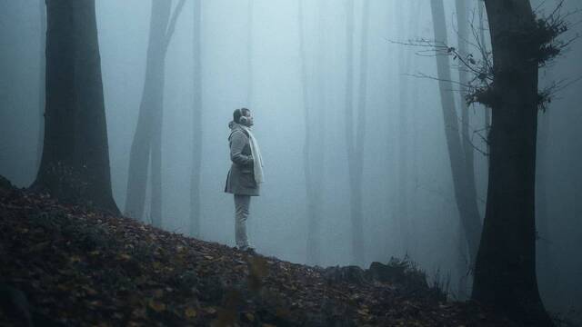 Una joven en un bosque cubierto por la niebla.