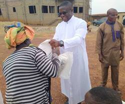 El padre Brown, con sotana blanca, habla con los habitantes de una aldea de Nigeria.