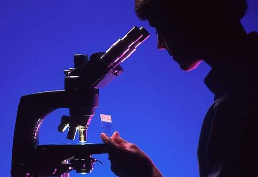 Silueta de una joven mirando un microscopio