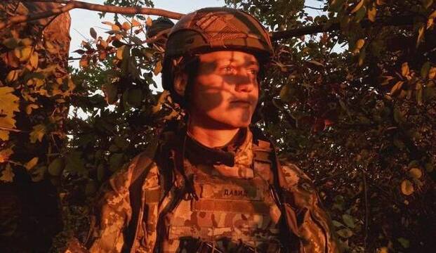 Artur Dron, poeta, con uniforme y caso de soldado, iluminado de rojo por una puesta sol