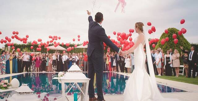 Novio y novia, vestidos, piscina, invitados y globos 